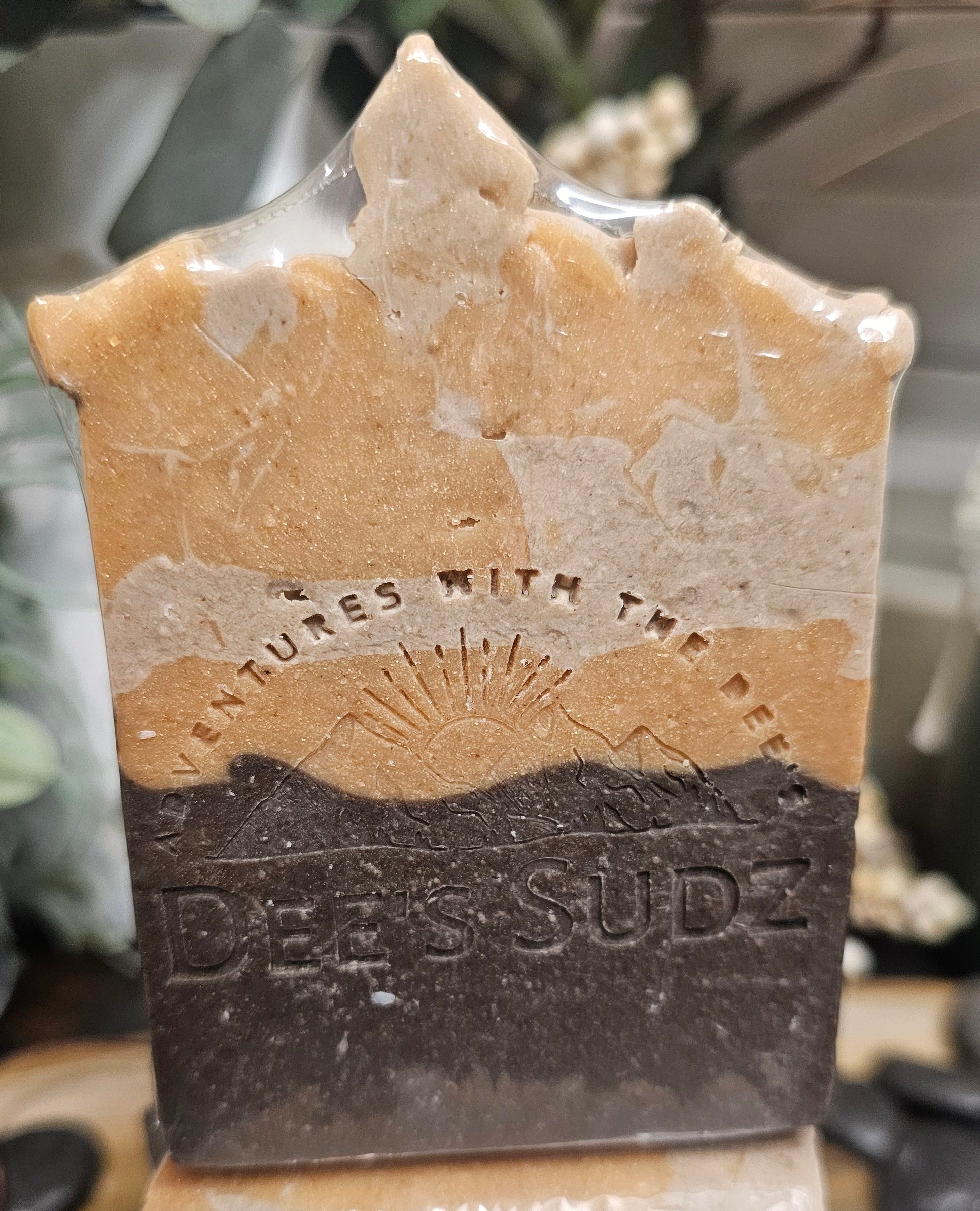 Rectangular handmade soap bar with the Dee’s Sudz logo, featuring layered tan, cream, and dark brown tones with a subtle swirl pattern.