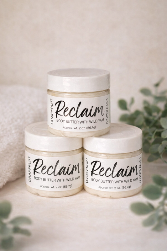 Three jars of 'Reclaim' body butter stacked on a light surface with greenery in the background.